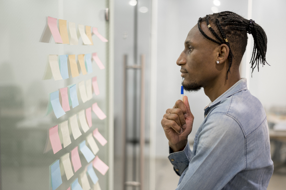 A non-technical cofounder looking at sticky notes on a glass office wall, showing a practical feature prioritization framework for an MVP scope.